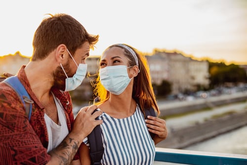 young couple on vacation wearing protective masks